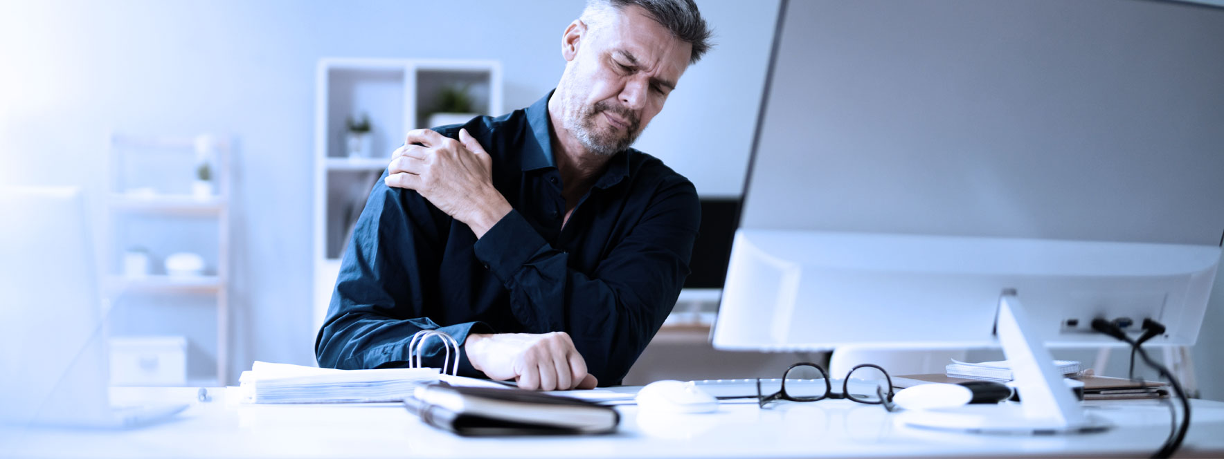 Un homme travaillant à l'ordinateur à une douleur à l'épaule
